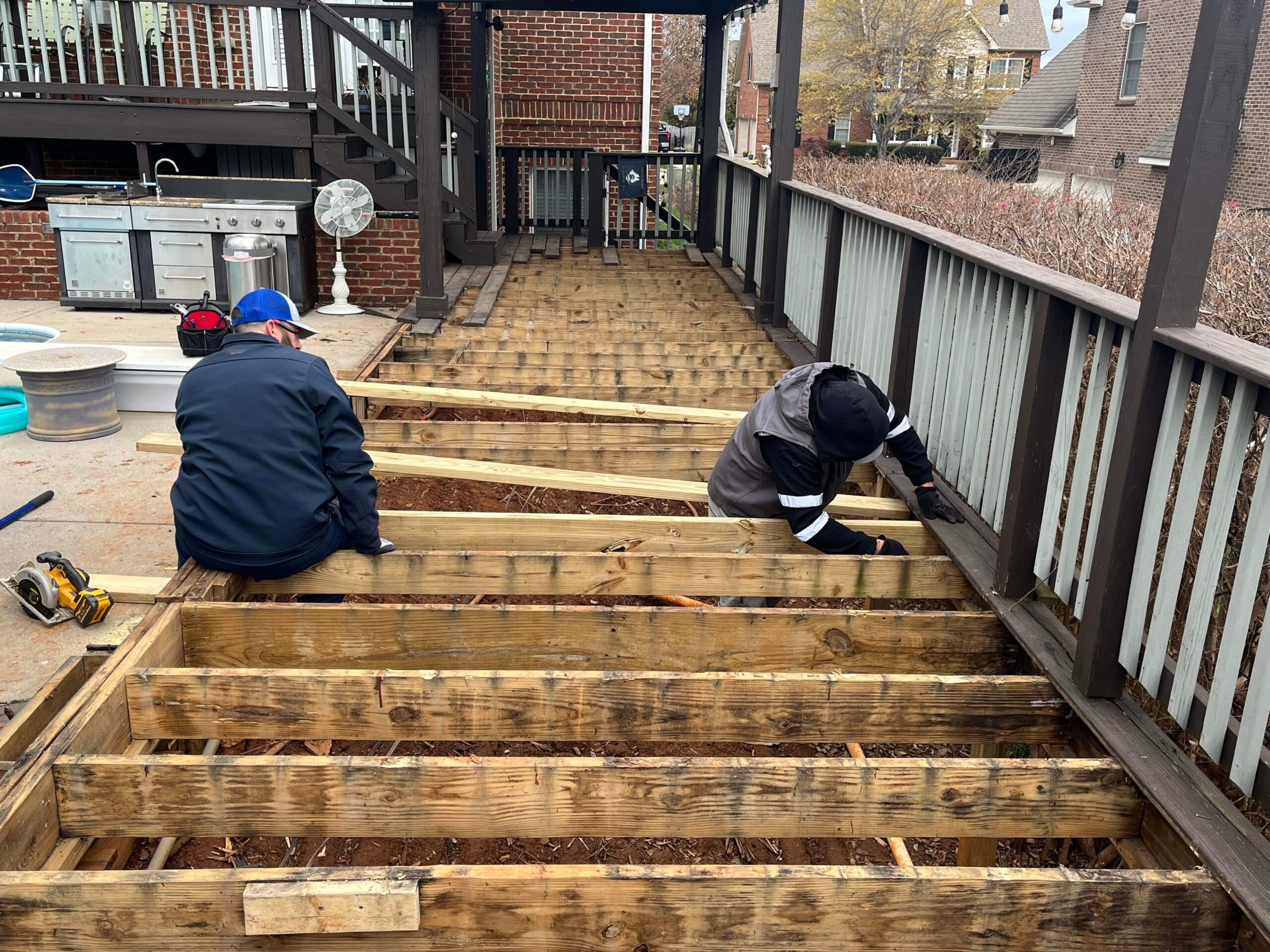 A worker drilling and securing new decking boards onto the frame.