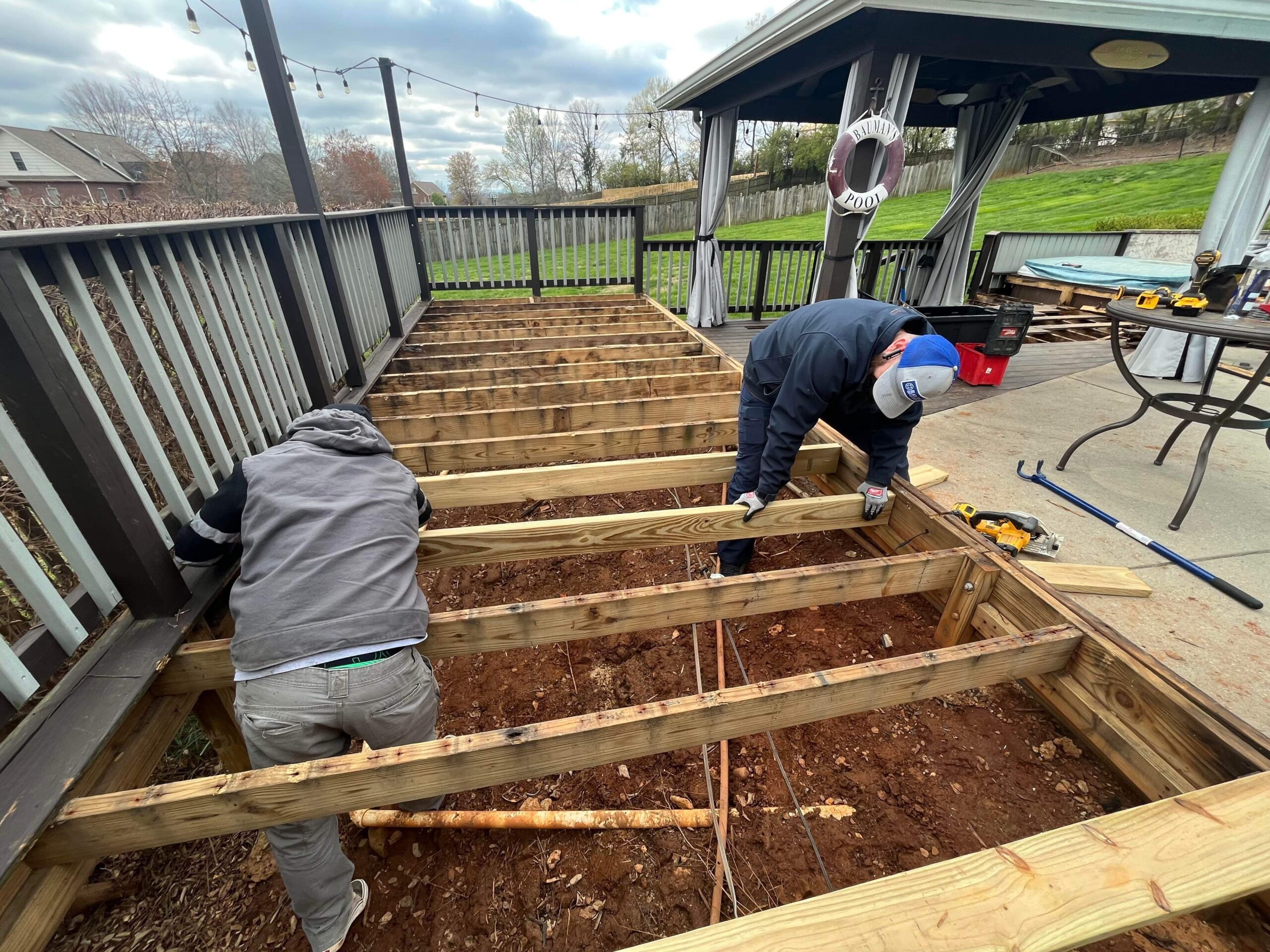 Workers reinforcing the deck's wooden frame for structural support.